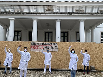 Estudantes posam com punhos para cima em frente ao prédio da Reitoria