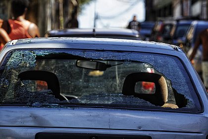 Carros que estavam estacionados na rua ficaram com marcas de tiros e vidros quebrados