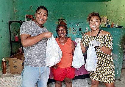 Alex Cruz e Alana de Carvalho, ambos da Frente Nacional Negros e Negras, distribuem alimentos para dona Rosa, moradora do Calabar