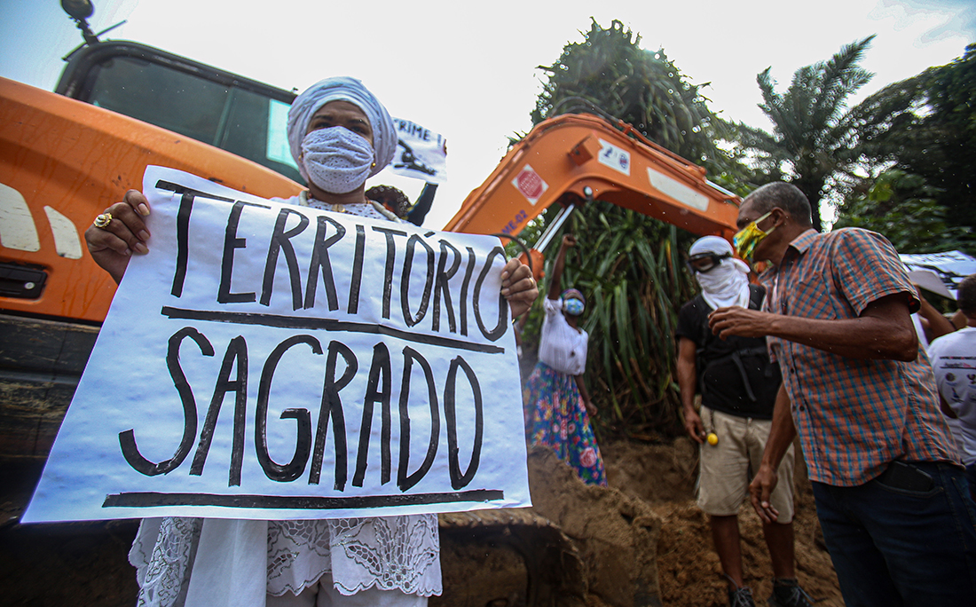Manifestantes cercaram a retroescavadeira que trabalhava no local com cartazes pedindo a paralisação das obras, respeito à cultura local e ao povo de matriz africana, que tem a lagoa como local sagrado.